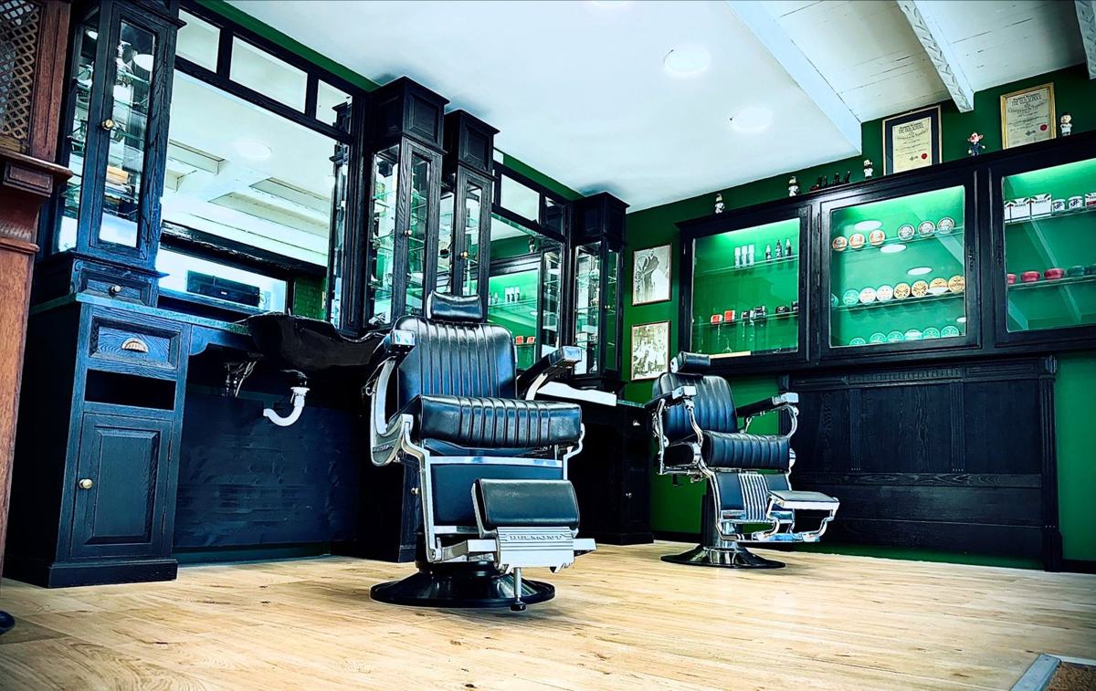 Le salon I Love My Barbe du Portel : fauteuils Belmont, vitrines noires et murs verts
